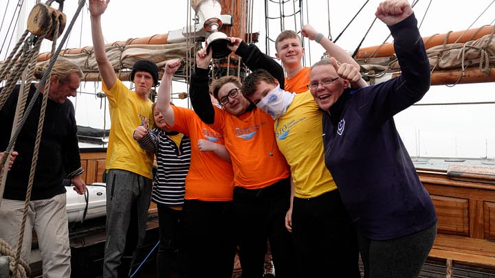 Crew on board Johanna Lucretia cheering and holding the trophy for the Spirit of the Race